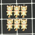 Top view of six cute resin cat charms with orange stripes and metal rings for DIY jewelry - Matte Light Yellow Cat