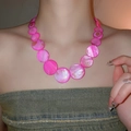 Detalle de un collar de cuentas de nácar rosa vibrante usado en el cuello de una modelo mujer - Rosa