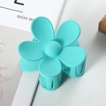 Detailed top view of a matte cyan flower hair claw clip on a modern minimalist magazine - 7cm / Cyan