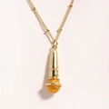 Macro shot of gold microphone pendant showing detailed mesh texture on stainless necklace - Yellow