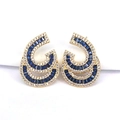 Detailed close-up of gold stud earrings with blue and clear pavé zircon stones - Dark Blue