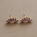 Dettaglio di orecchini a ventaglio dorati con cinque zirconi viola su fondo marrone - Oro (Zirconia Viola)