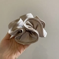 Elegant beige satin scrunchie with French vintage ruffle design held in hand - Off-white