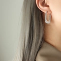 Orecchini geometrici a U in argento con trama a righe sottili indossati da modella - F671 Forma U Righe / Color Acciaio