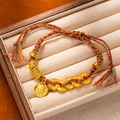 Detailed close-up of woven red cord bracelet with ancient gold coins and deity charm - L269-6 Fortune Path
