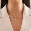 Close-up of golden letter I pendant with blue evil eye bead on a twisted chain - Letter I (N1339)