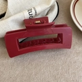 Detailed macro view of a dark red square hair claw clip with a golden metal spring - Red