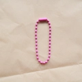 Single 2.4mm pink lacquered metal bead chain with connector on beige paper background - Rose Red