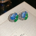 Détail de boucles d'oreilles vintage avec pierres bleues et vertes dans un écrin beige - Clous d'oreilles fleur feuille goutte d'eau en résine et strass avec tige en argent