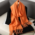 Detailed view of an orange cashmere-like scarf with soft tassels on a stylish background - Orange