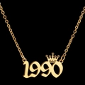 Macro shot of gold 1990 number necklace with crown pendant on black background - 1990 / Gold