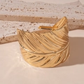 Vista detallada de la textura de hoja en el brazalete abierto de metal dorado elegante - Dorado