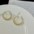 Macro-opname van 14K vergulde gedraaide oorringen op een vintage keramische achtergrond - Vintage Gedraaide Hoop / Goud