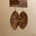 Detail view of leather leaf-shaped earrings with vintage butterfly print on wooden patterns - Butterfly Pattern