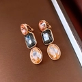 Detail of vintage gold earrings with pink, black and champagne crystals on brown background - Three-Stone Ear Clips (Gold-Pink-Grey)