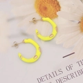 Close-up of yellow enamel C-shape hoop earrings with gold metal teardrop accents - Yellow