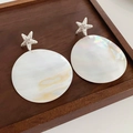 Macro de boucles d'oreilles en coquille avec étoile de mer argentée sur bois - Forme d'étoile de mer / Argenté