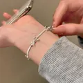 Detailed view of silver bow-shaped snake chain bracelet worn on a woman's wrist - Silver/Bowknot