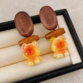 Macro view of brown bear resin pendants and natural wood links in a soft jewelry box - Oval Wood Resin Bear (WE5818) / Coffee/Yellow