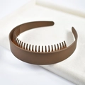 Detailed macro view of a brown matte headband with non-slip teeth on a beige velvet tray - 3# Wide Lacquered Brown Toothed Headband