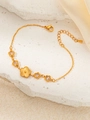 Détail d'un bracelet doré avec étoiles, fleurs et zircons blancs sur roche et soie - Bracelet Zircone Étoile - Blanc
