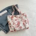 White canvas tote bag with red flower pattern and side pocket on a textured background - Red
