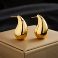 Macro view of gold-plated teardrop earrings with a high-polished mirror finish on silk - Gold