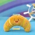 Detailed view of the cute croissant plush keychain with a smiling embroidered face - Croissant / 7x12cm