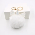 Close-up of white plush unicorn pom-pom keychain with glittery horn and gold hardware - Unicorn Gold Keychain / White