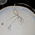 Macro detail of beaded necklace with bow design and silver heart charms on a white plate - Silver Bowknot Style