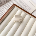 Nahaufnahme der beigefarbenen herzförmigen Haarklammer aus Acetat in einer Geschenkbox - Creme