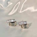 Close-up of zircon earrings with gold interlaced metal on champagne silk background - Silver Zircon Crossing Stud Earrings