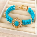Detalle de una pulsera vintage con cuentas turquesas y colgante floral de strass - Pulsera-Dorado-Azul