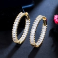 Macro detail of gold C-shaped hoop earrings with baguette-cut cubic zirconia inlay - Gold