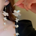 Macro detail of long white flower tassel earrings with pearl luster and gold chains - Four-Layer Flower Ear Hook Style / Silver/White