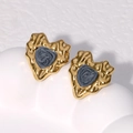 Detalle macro de pendientes de corazón de oro de 18K con centros gris textura - Negro Perlado