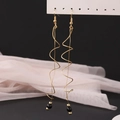 Detail of gold spiral tassel earrings with black beads on a soft pink fabric display - KC Gold (12323)
