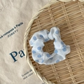 Chouchou bleu clair à pois posé sur un plateau tressé beige avec fond de tissu vintage - Pois Bleu Clair