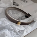 Detail eines taupefarbenen Samt-Stirnbands mit kleinem goldenem S-Metall-Dekor - Khaki