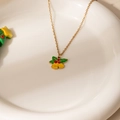 Detalle de collar con campana dorada y hojas de acebo sobre plato de cerámica - Collar de campana de hoja verde