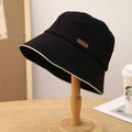 Black cotton bucket hat with beige piping trim and leather patch on wooden stand - M (56-58cm) / Black