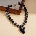 Dettaglio di perle in acrilico con pendente a cuore e distanziatori dorati per collana retro - Collana / Nero