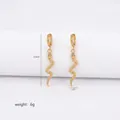 Detail of gold snake drop earrings with scale texture and green zircon eyes, 5.5cm long - Gold