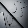 Detailed view of silver titanium steel box chain and cylindrical pendant on black leather - Black
