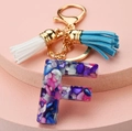 Detail of resin letter F keychain with colorful stones, gold chain and double tassels - Letter F