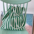 Borsa in tela a righe bianche e verdi con manici spessi su una sedia color menta - Verde