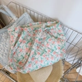 Detail of floral quilted cotton tote bags with rose prints in a stylish woven basket - Green Leaf Red Rose