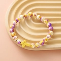 Detail of colorful marble beads and yellow stone cross charm on a ripple tray - Yellow Purple White Spotted Yellow Cross