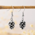 Bohemian silver pinecone earrings hanging on a branch with a soft floral backdrop - Pine Cone Pendant Style (9790)