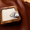 Detail view of silver oval ring with grey pearl and pavé accents in a wooden jewelry box - Adjustable Oval Grey Pearl (HR1570)
